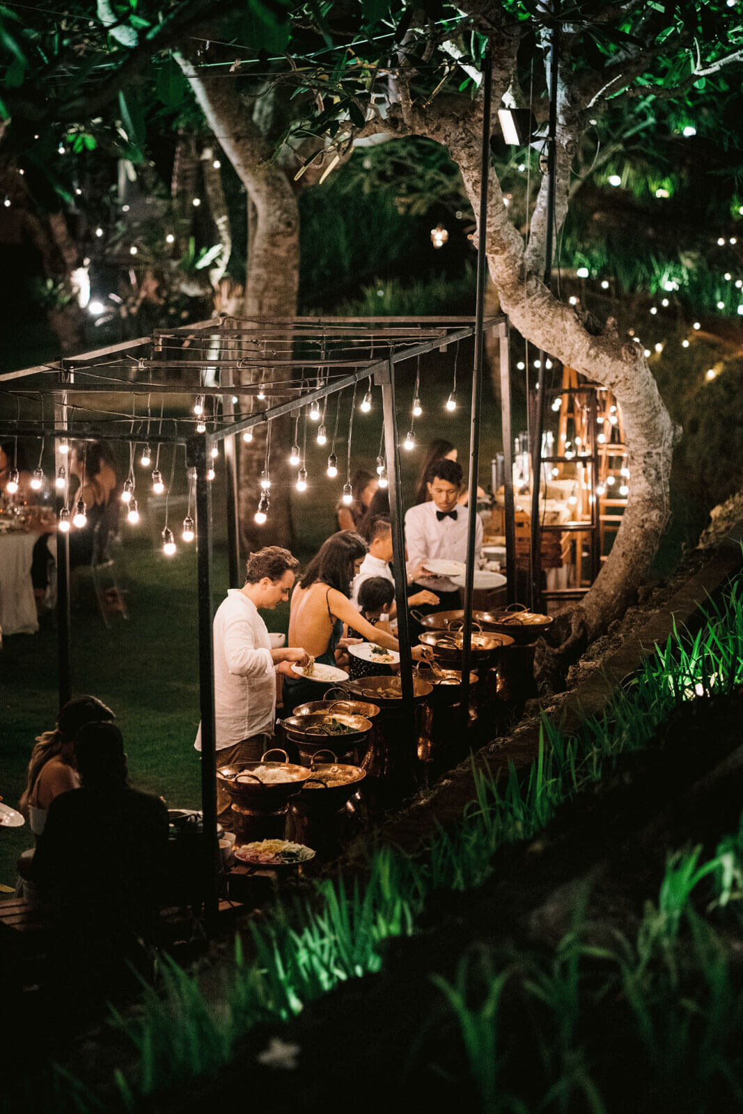The wedding guests are getting food in the outdoor buffet area in Khayangan Estate, Bali, Indonesia. Image by Jenny Fu Studio