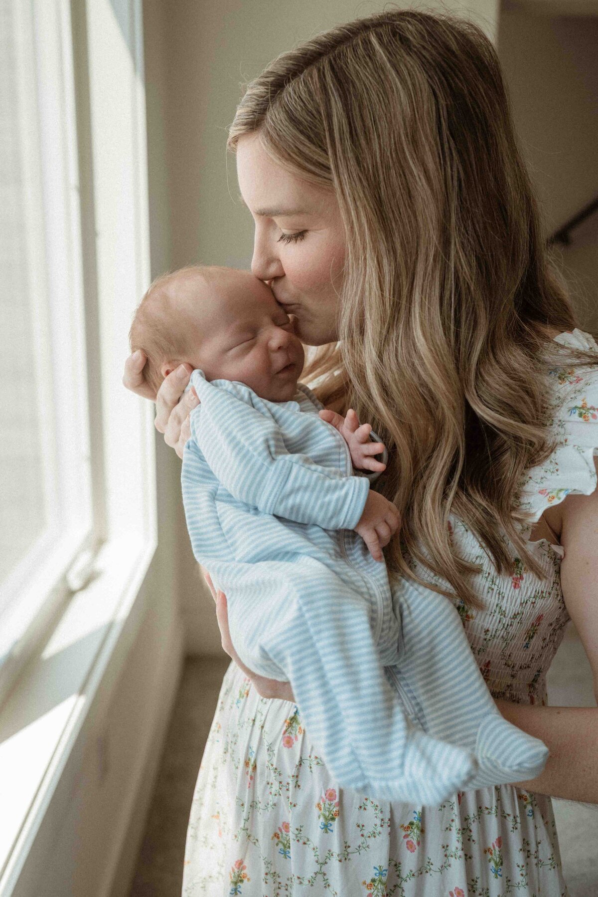 mother kissing her newborn baby boy on the head during an in-home newborn session with pittsburgh newborn photographer kristin wieskamp