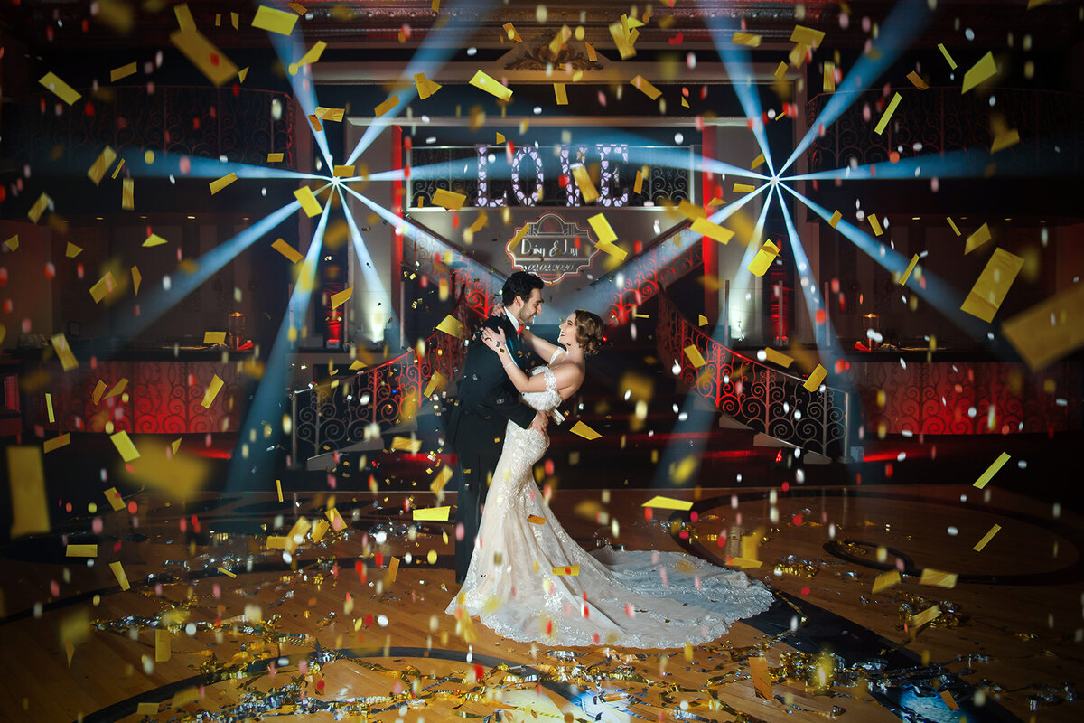 Bride and groom embrace under confetti at their wedding