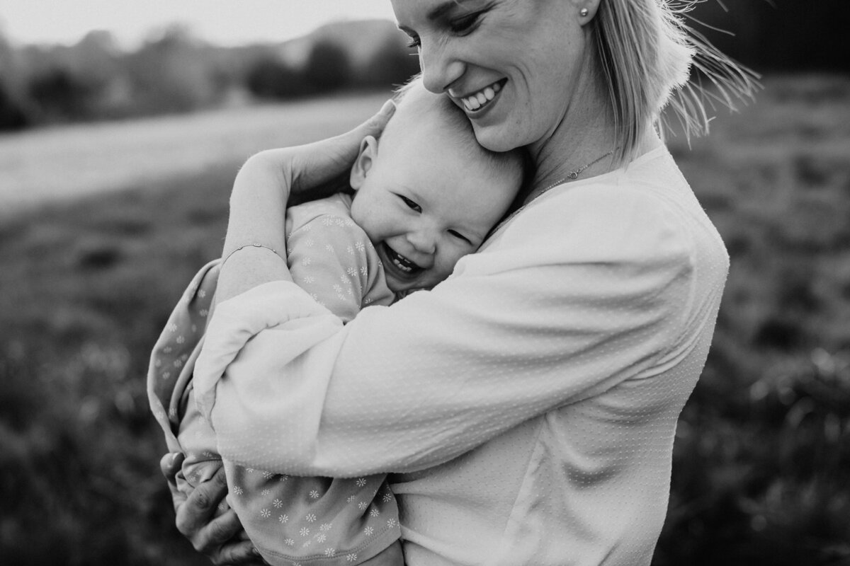 mom smiling holding laughing baby