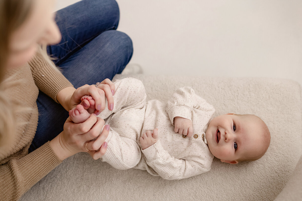 A six-month-old rests on their tummy, lifting their head with pride during their milestone photoshoot.