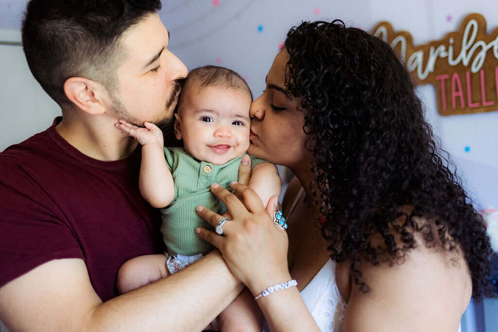 Two parents kiss their child's cheeks.