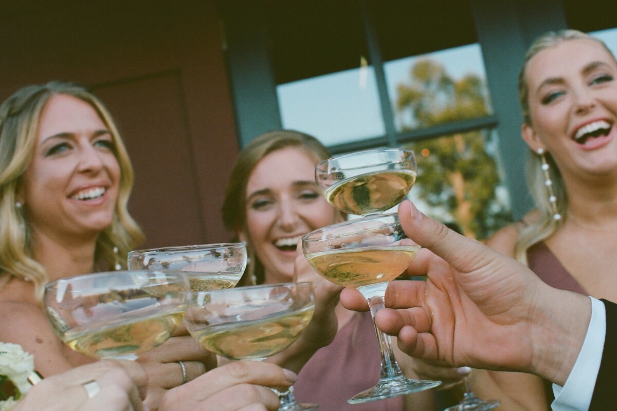 A Portra 400 35mm film scan of a wedding party toasting with champagne. Captured by Fort Worth wedding photographer, Megan Christine Studio