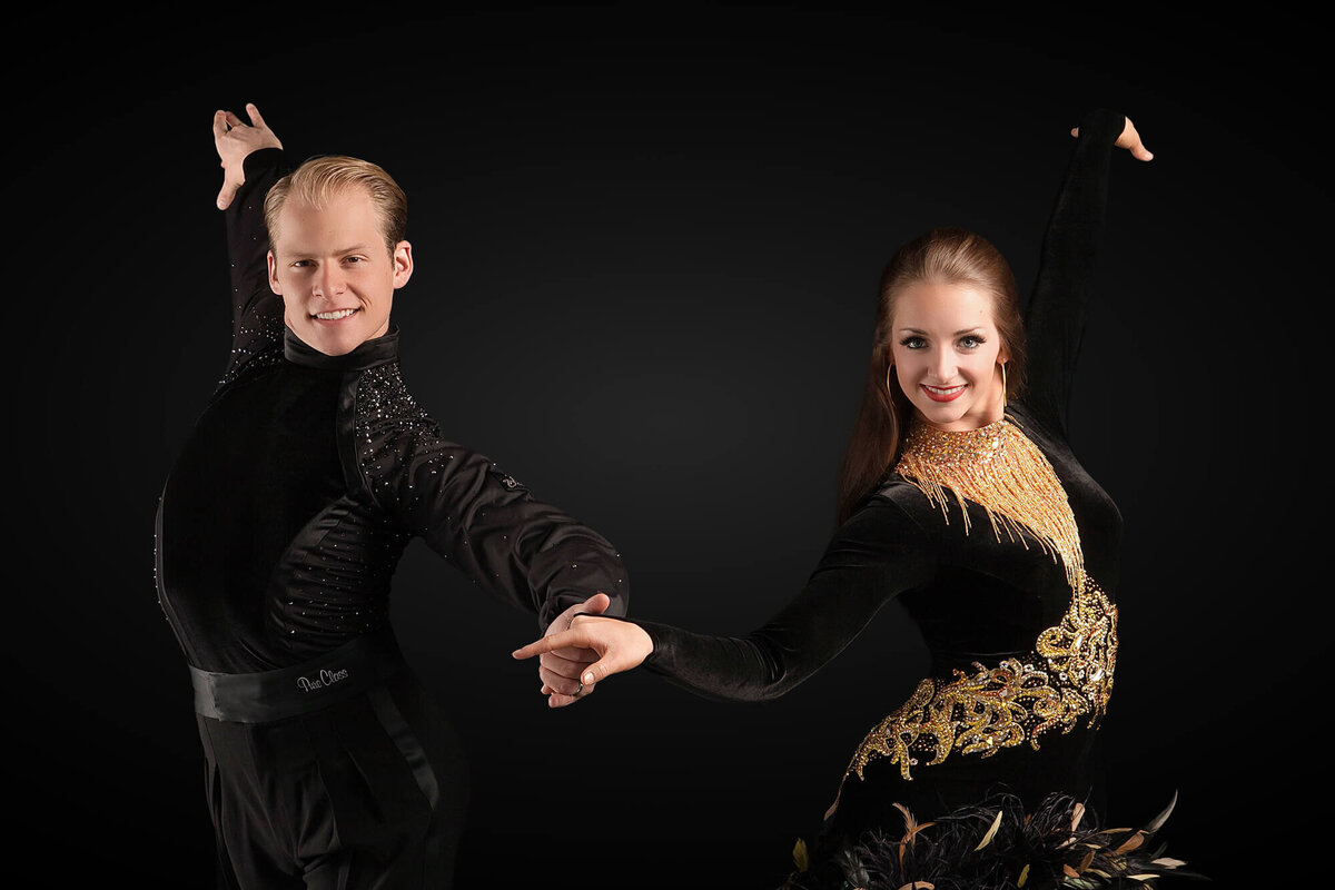 Ballroom Dance Portrait of a couple holding hands in a cross-over break cha cha step on a black backdrop