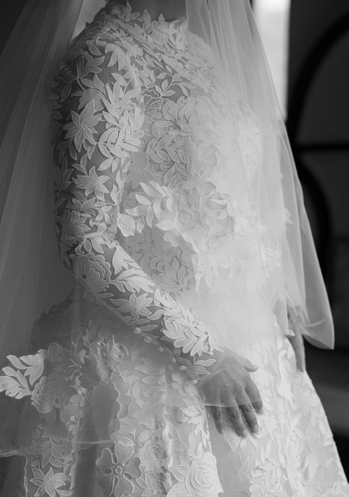 Close-up black and white detail of the bride’s long-sleeve lace wedding gown at Castle Ladyhawke.
