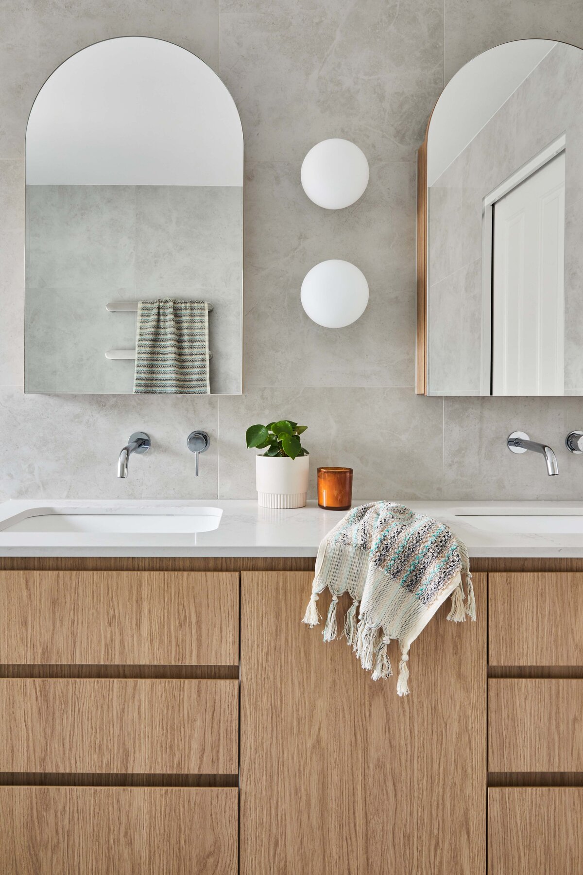 Light-filled living room with grey sectional sofas, sheer curtains, round coffee tables and layered neutral decor styled by interior designer in Williamstown, Melbourne.
