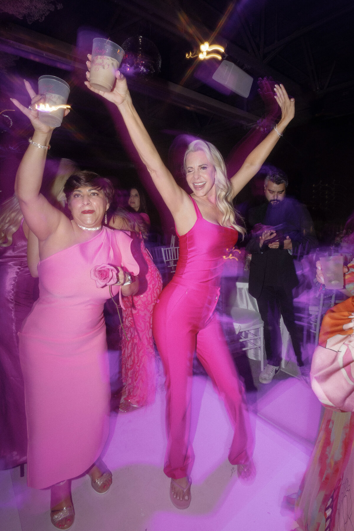 wedding guests wearing pink dancing at reception