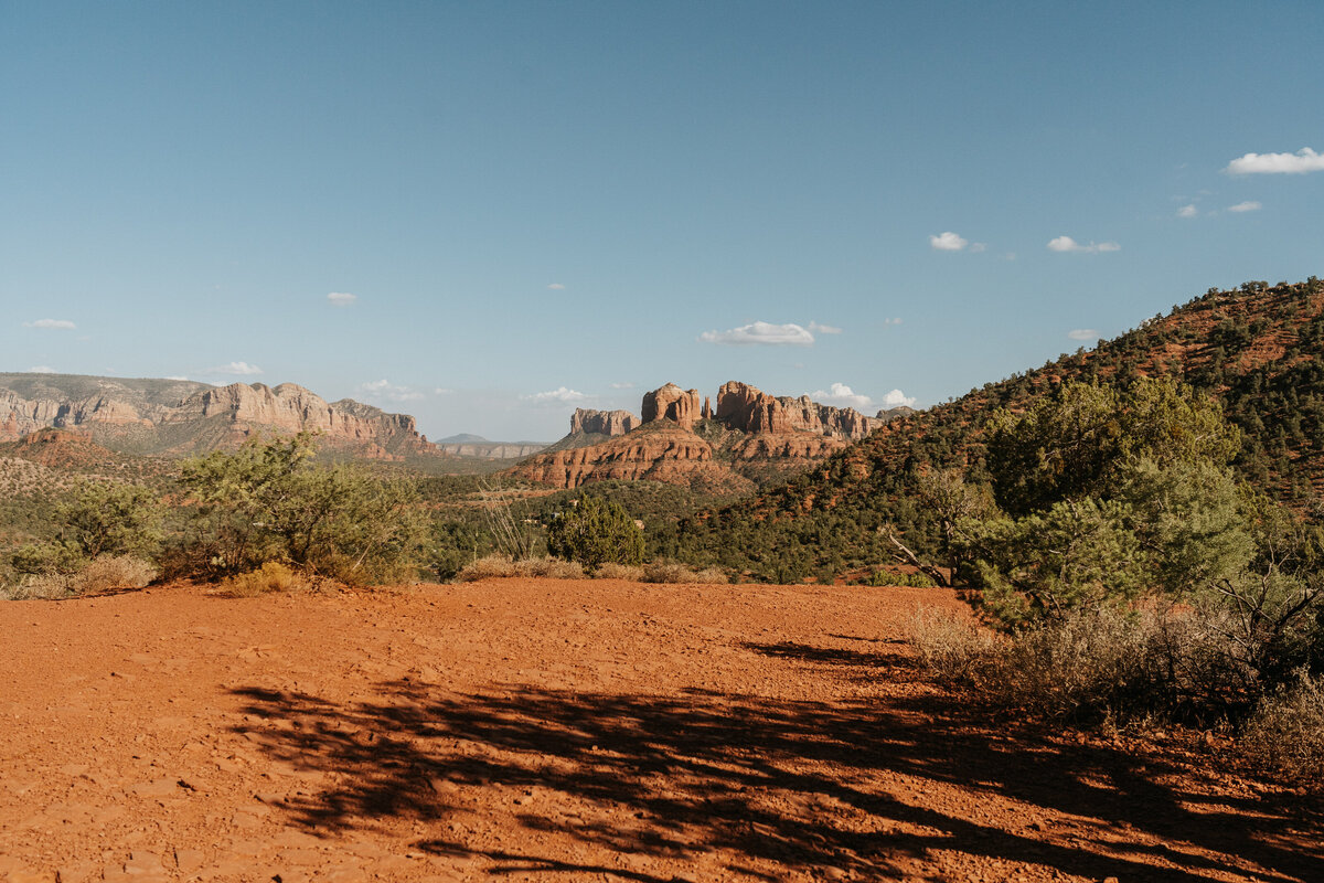 A dirt area in front of a red rock formation 