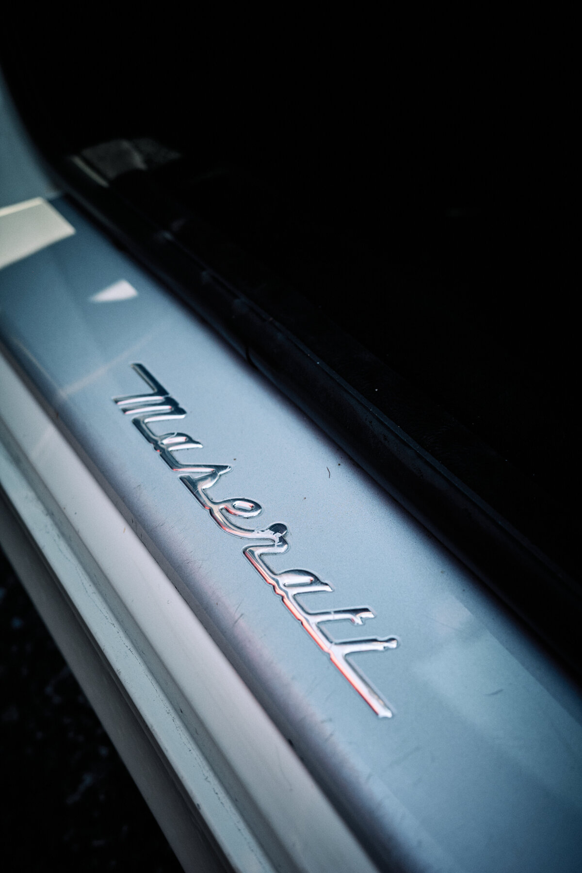 Close-up of a chrome Maserati logo on the door sill plate, showcasing the premium craftsmanship and luxury branding of the vehicle.