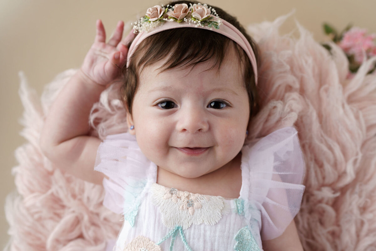 Baby Girl in Floral Embroidered Romper on Pink Blush Flokatti