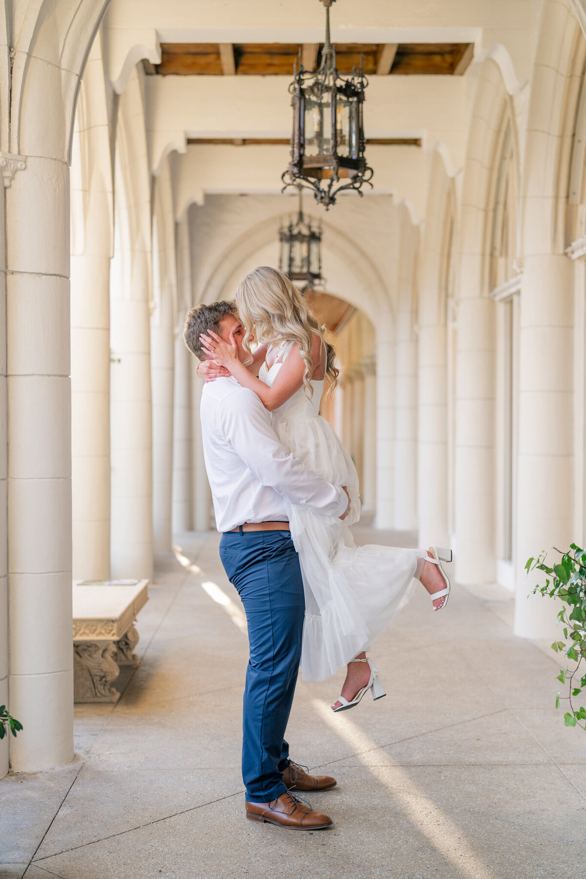 Couple embracing in lift pose in columned hallway