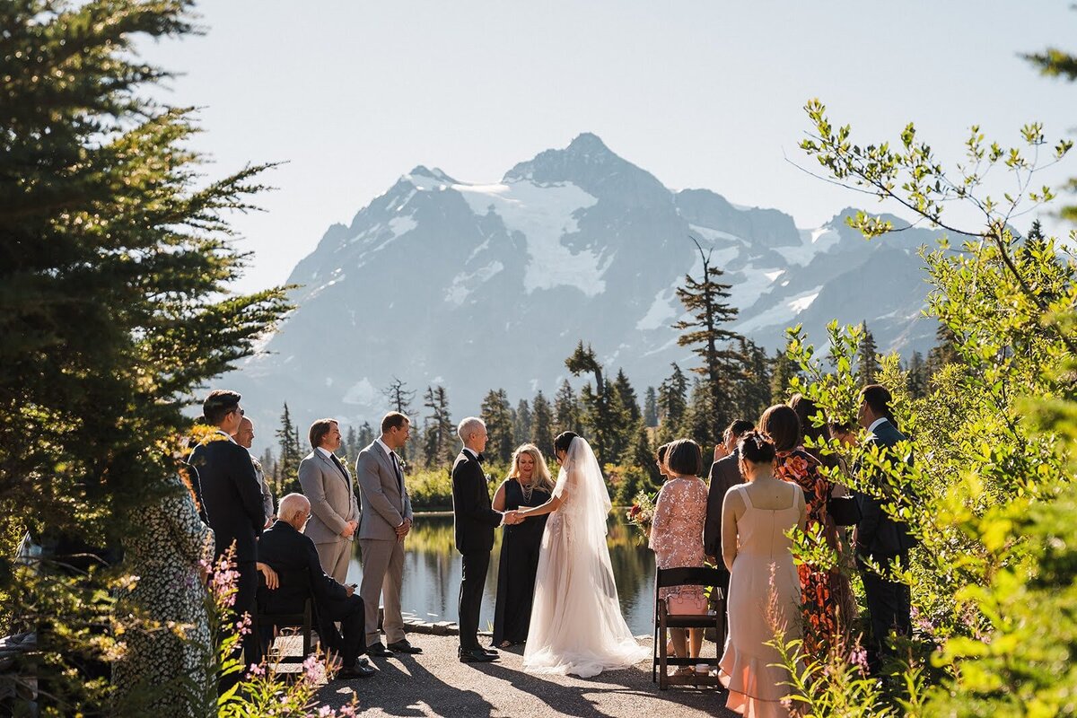 Bride & groom holding hands during intimate wedding ceremony in front of Picture Lake near Mount Baker!