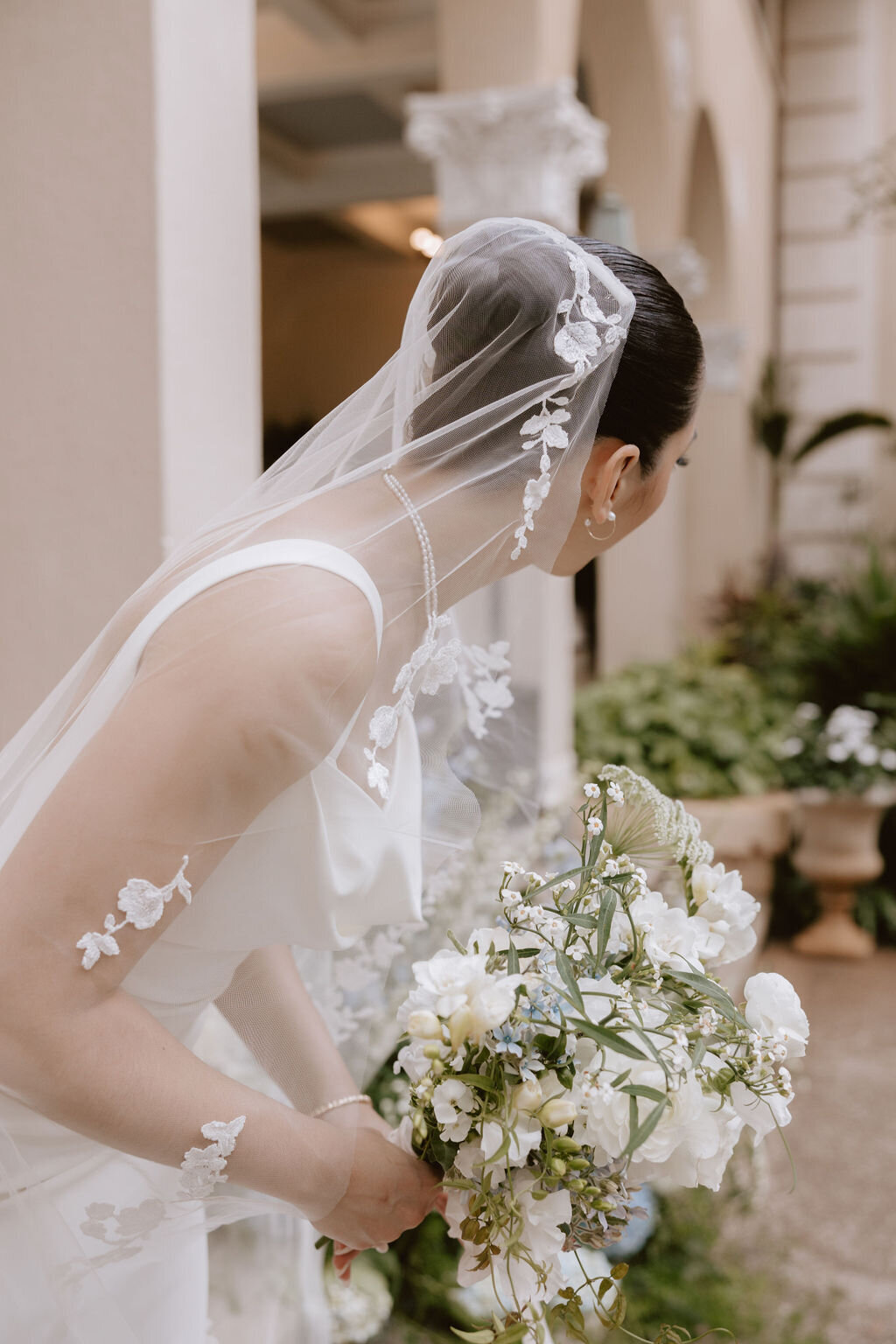 bride looking away, showing veil draping over her bun holding flowers