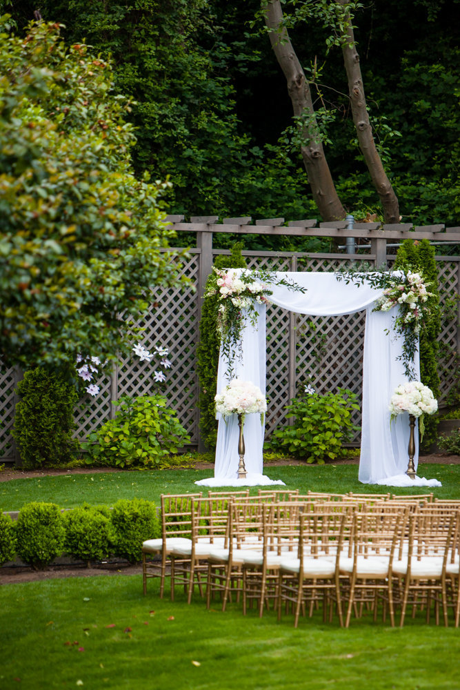 Outdoor garden wedding ceremony on the lawn with gold chiavari chairs.