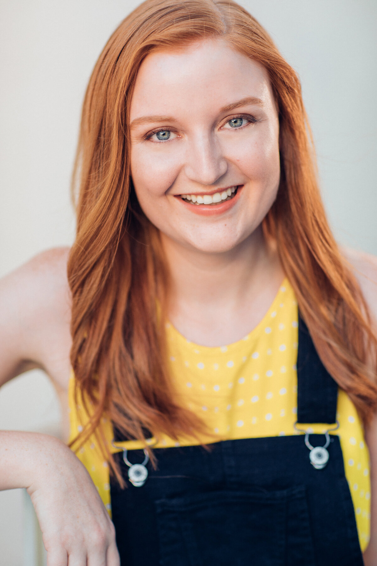 Headshot Photograph Of Young Woman In Dark Blue Jumper And Yellow Sleeveless Los Angeles