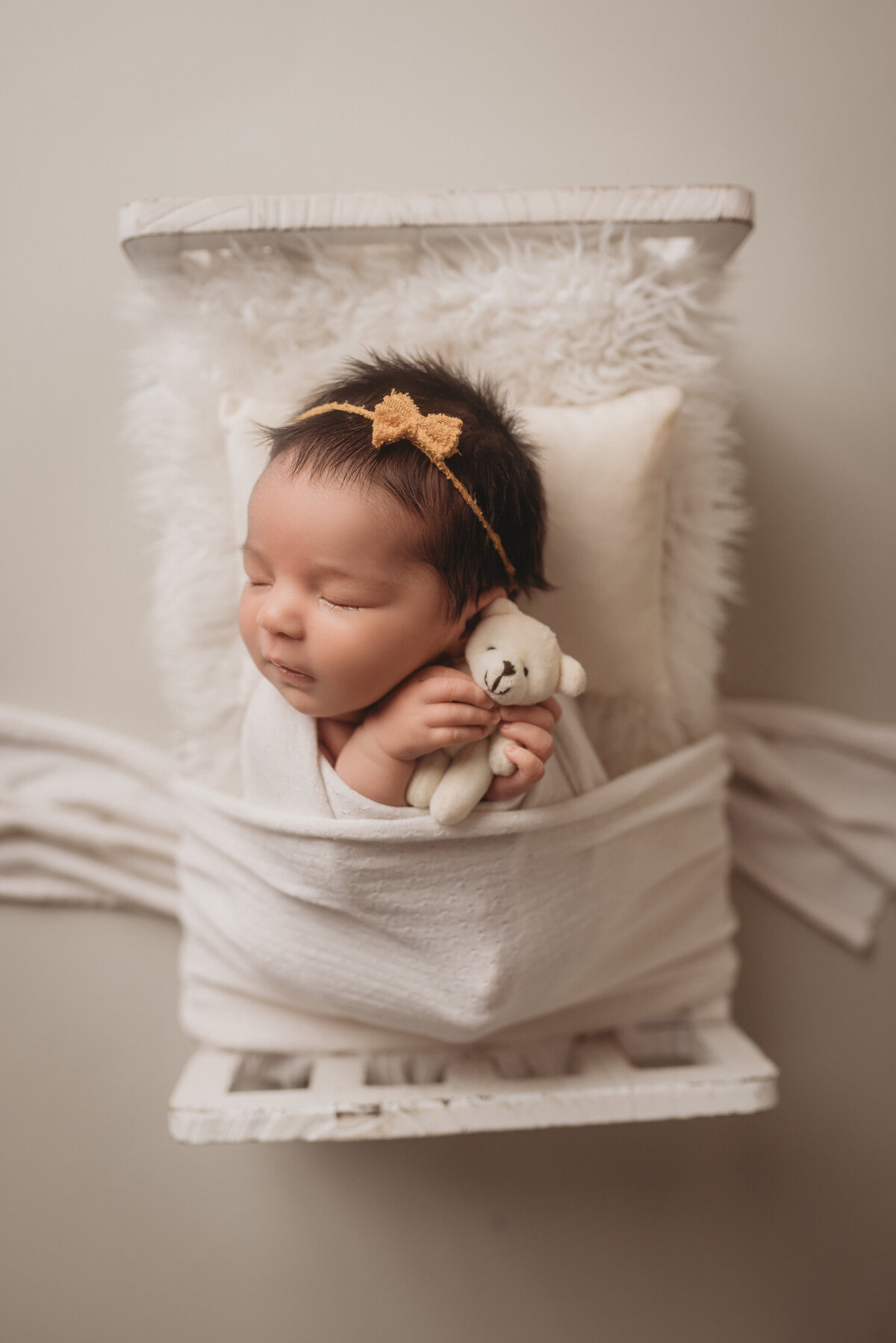 Baby girl, 2 weeks old, posing at Atlanta portrait studio for newborn portraits with little teddy bear in her hand