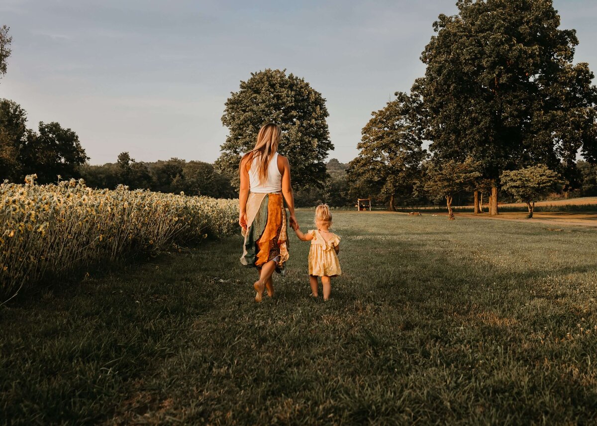 A mother and daughter enjoying a stroll through a field at sunset, captured beautifully by a Pittsburgh family photographer.