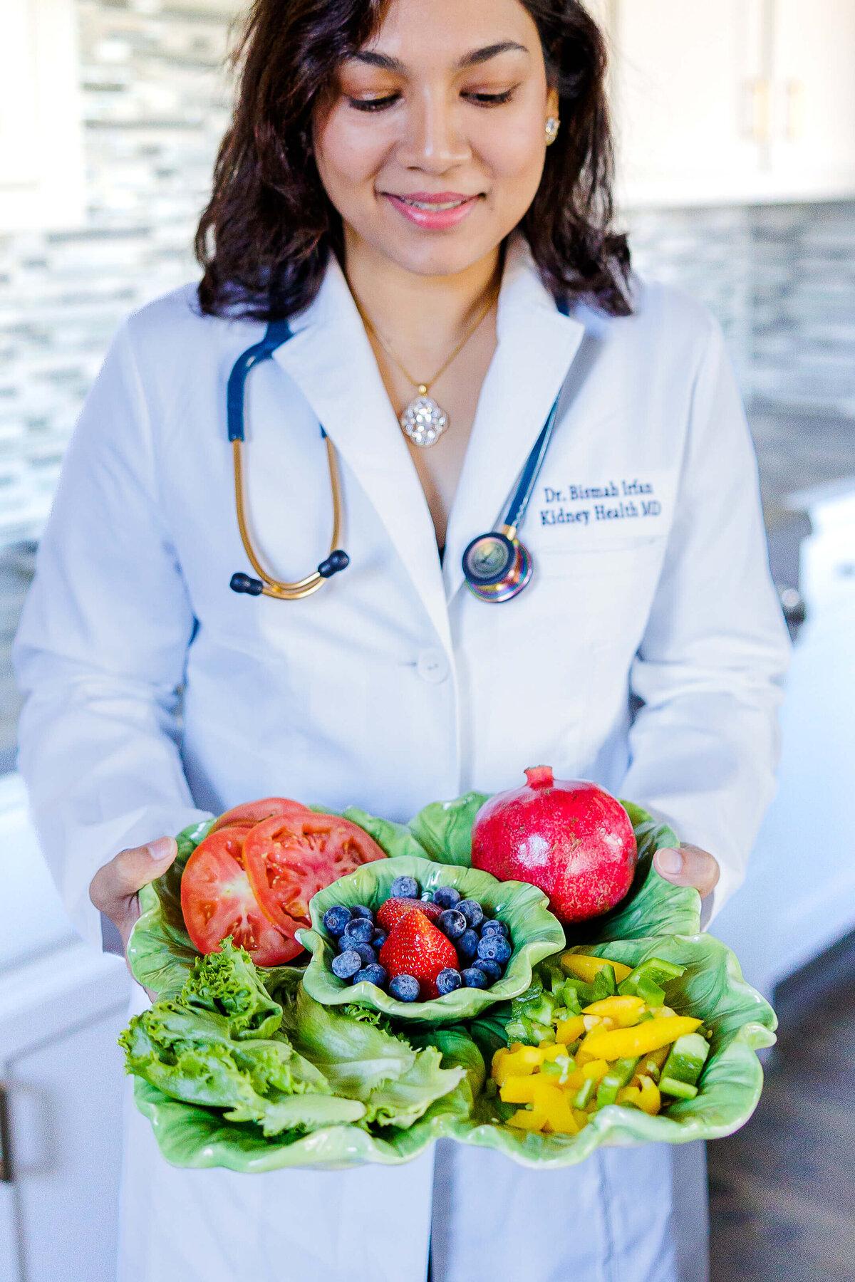 Lady in dr. coat holding plate of fruit