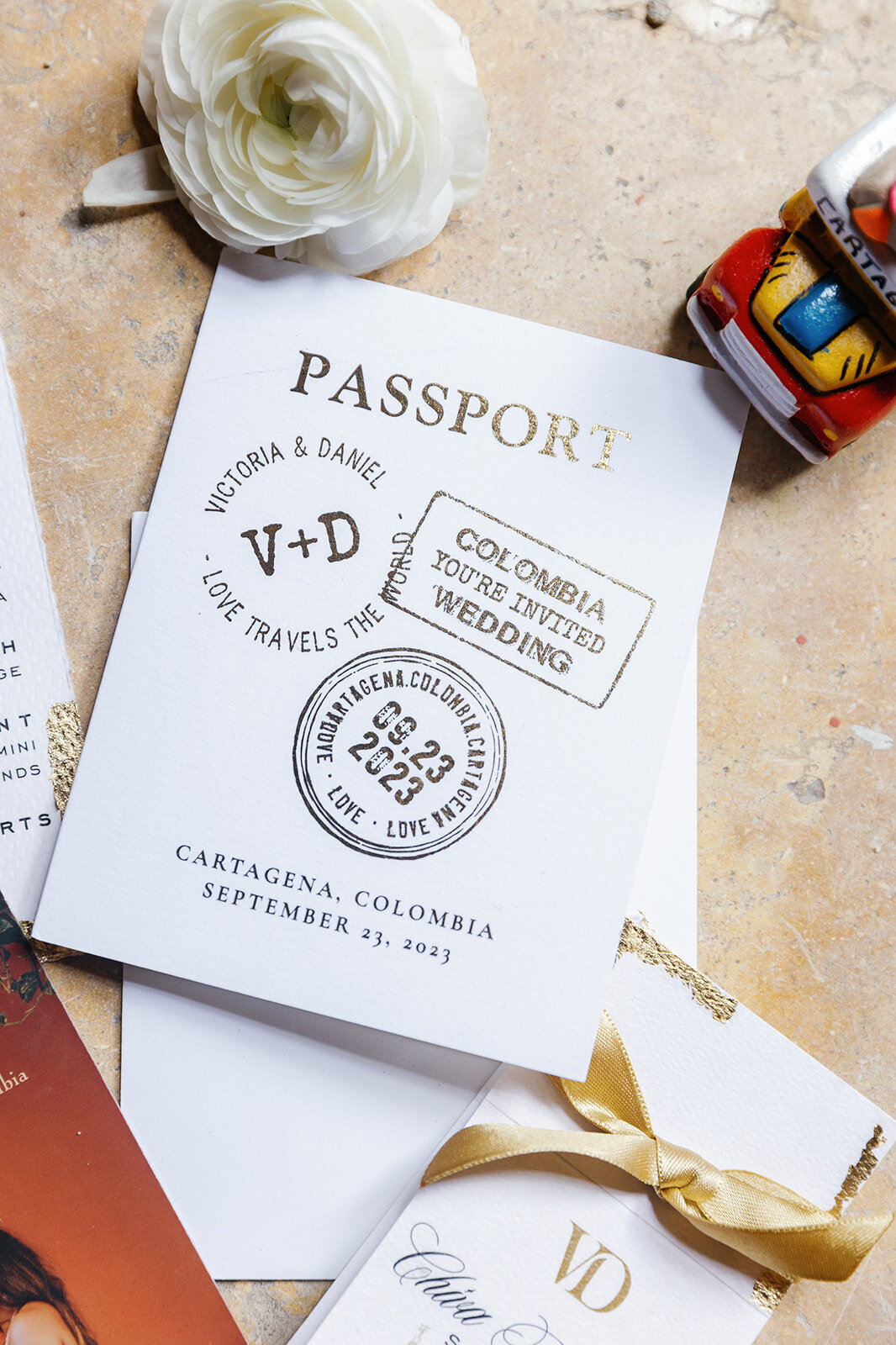 A detailed look at Victoria and Daniel's Cartagena destination wedding invitation, featuring gold accents and a passport theme.