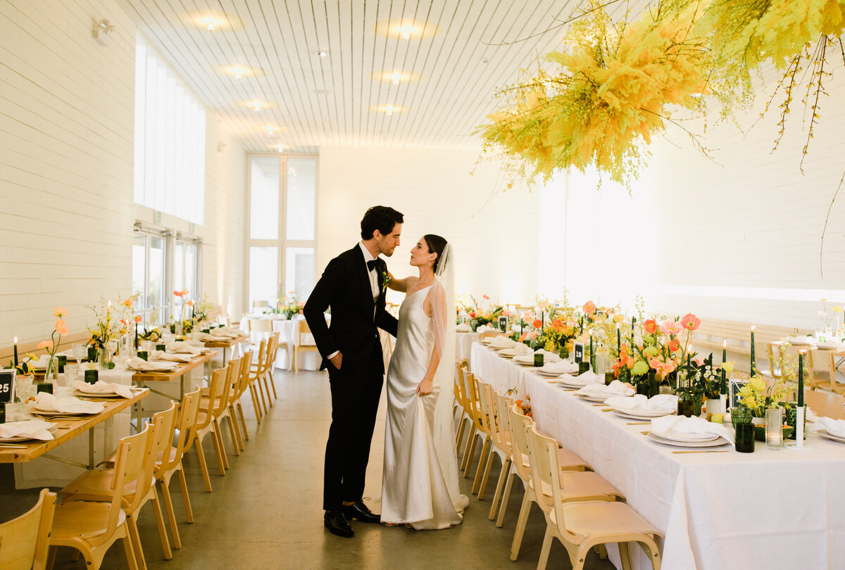 Bride and groom standing amongst reception tables with bold pops of yellow at Prospect House Austin