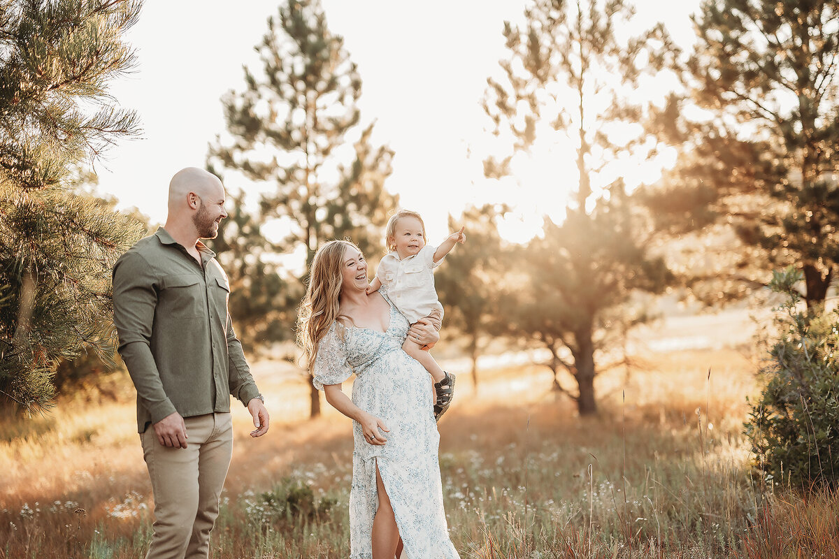 pregnant woman holding her son while he points to a tree