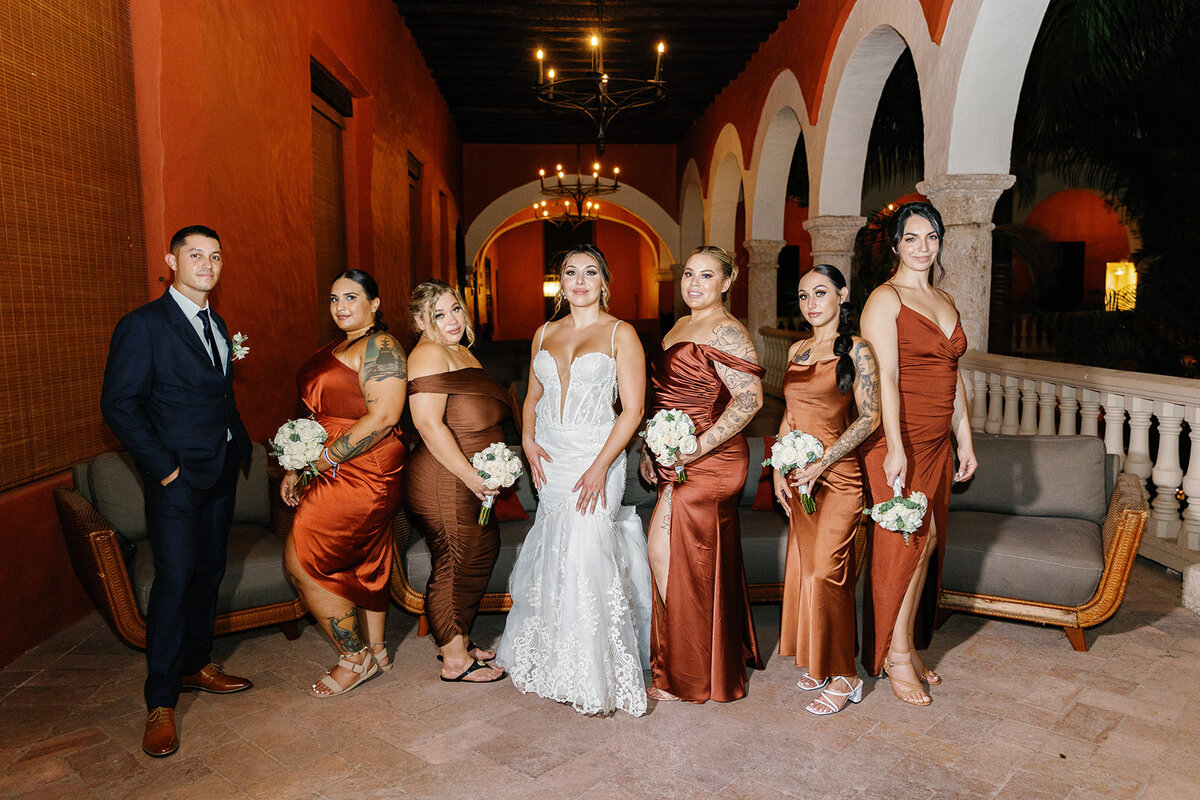 Victoria poses with her bridesmaids in elegant rust-colored satin dresses at their Cartagena Colombia wedding.