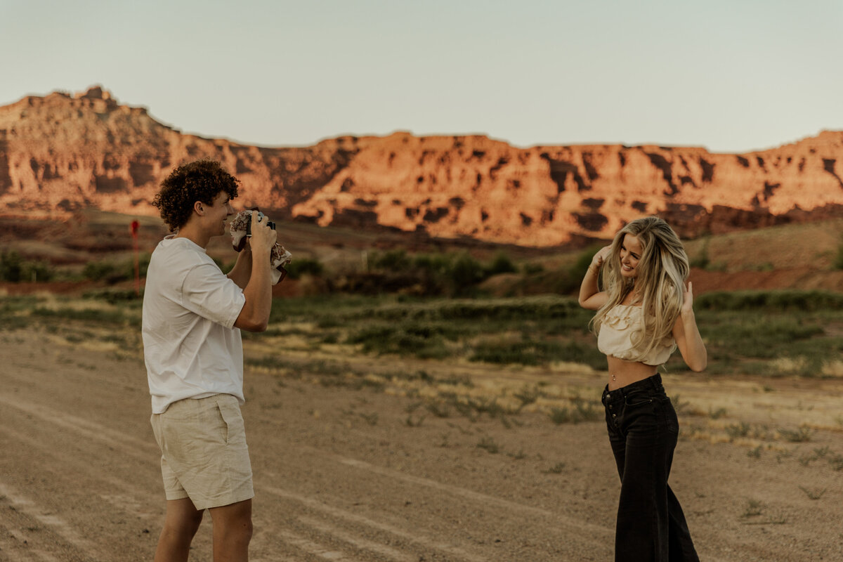 Boyfriend taking photo of girlfreidn while they play in the Utah Desert 