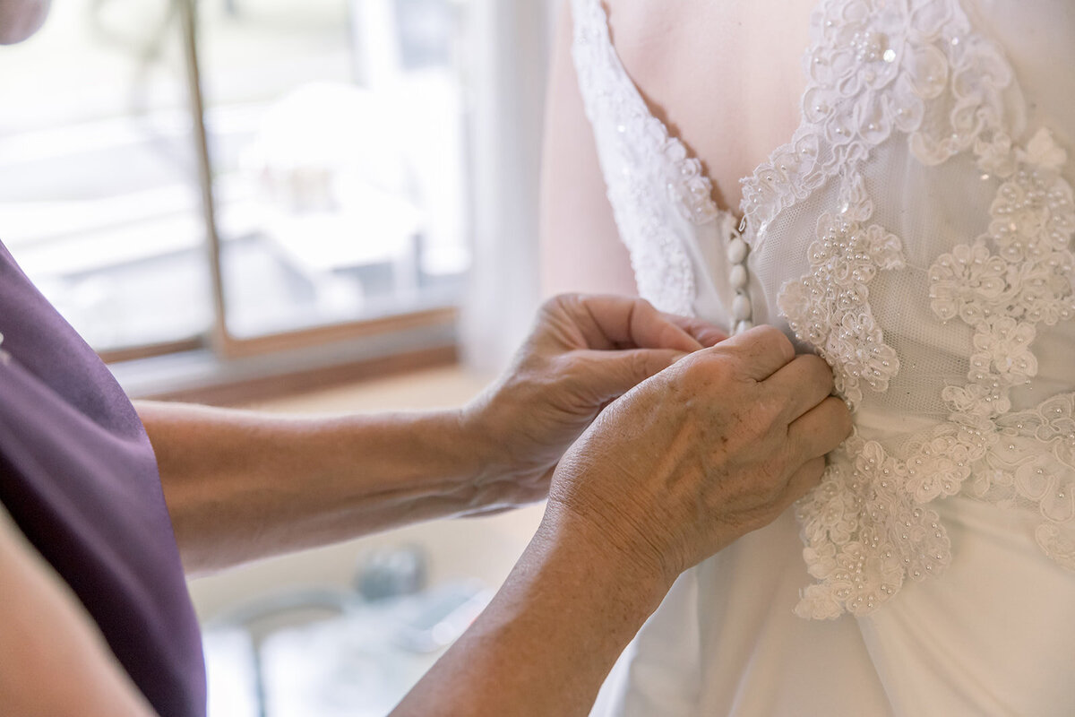 Back of a wedding dress with someone buttoning it up