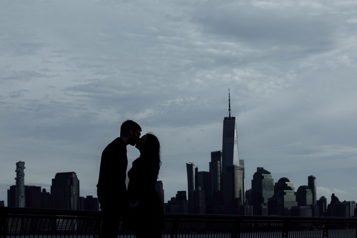 Couple kissing in spring silhouette with NYC skyline during engagement photo in Hoboken New Jersey