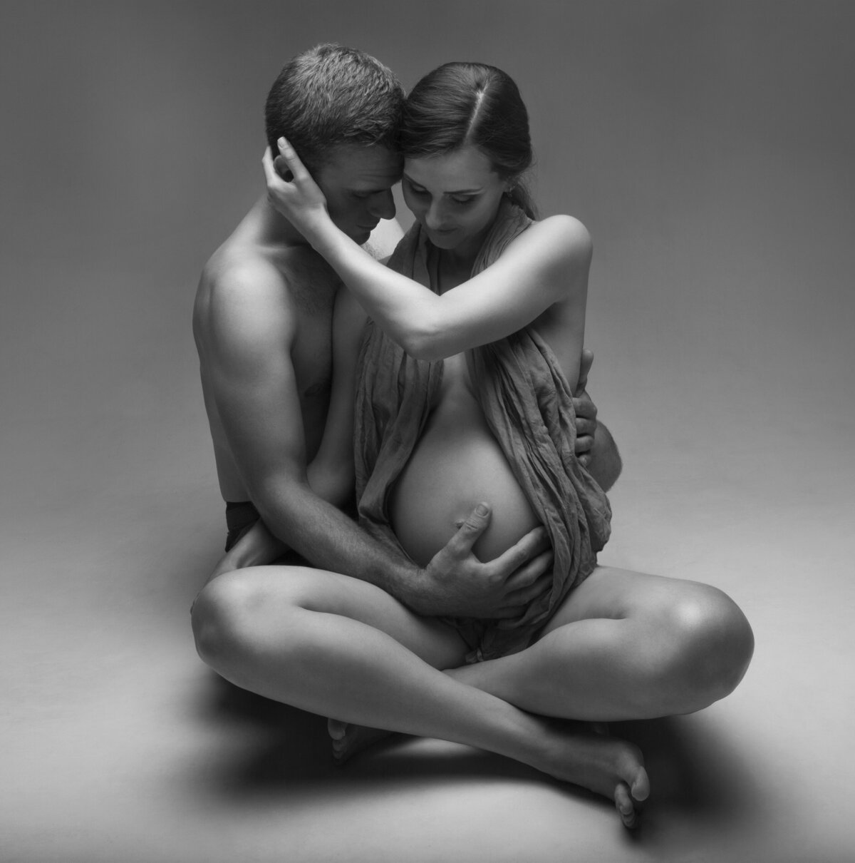 young-couple-sitting-against-gray-background