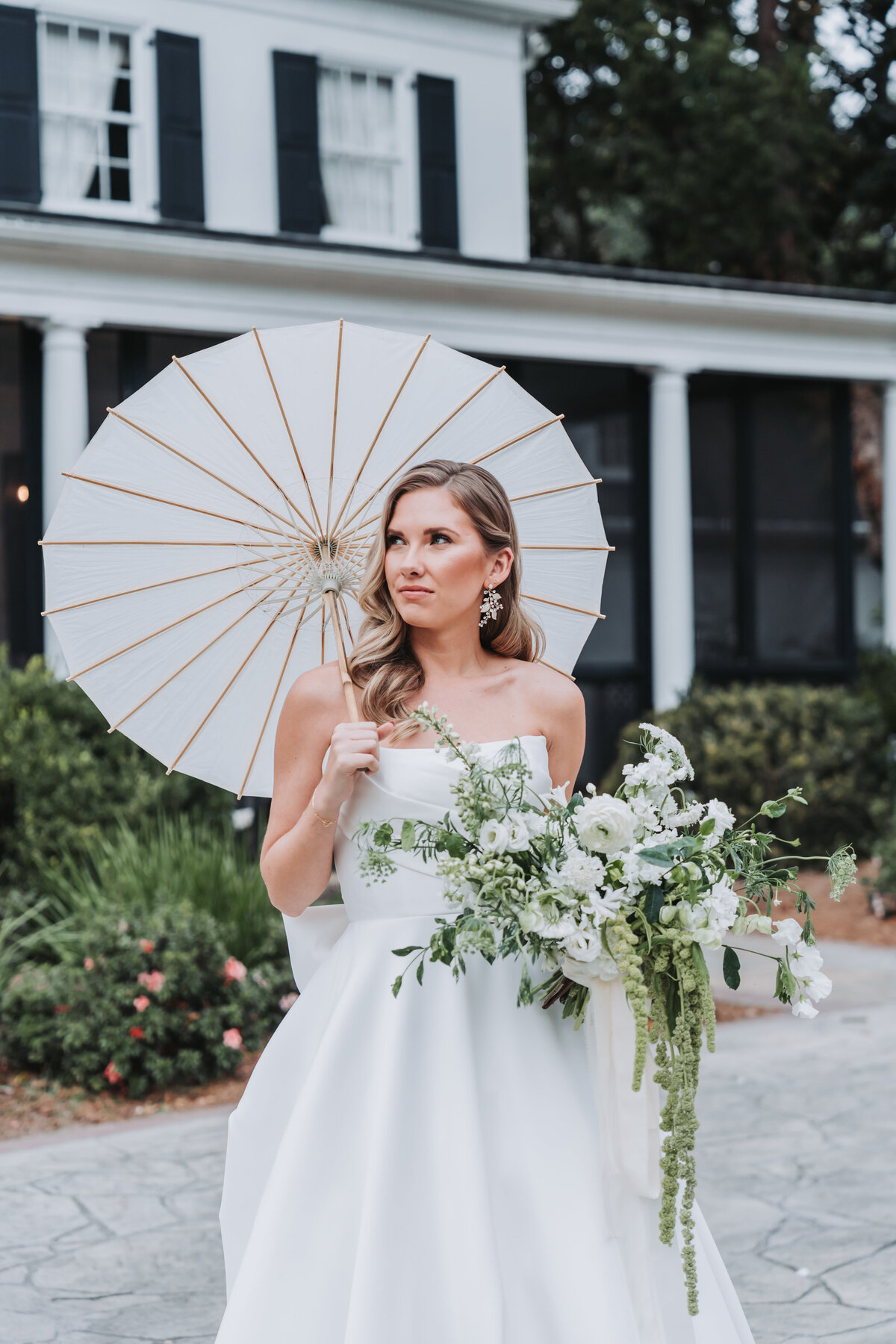 Bride holds bouquet and umbrella in hand