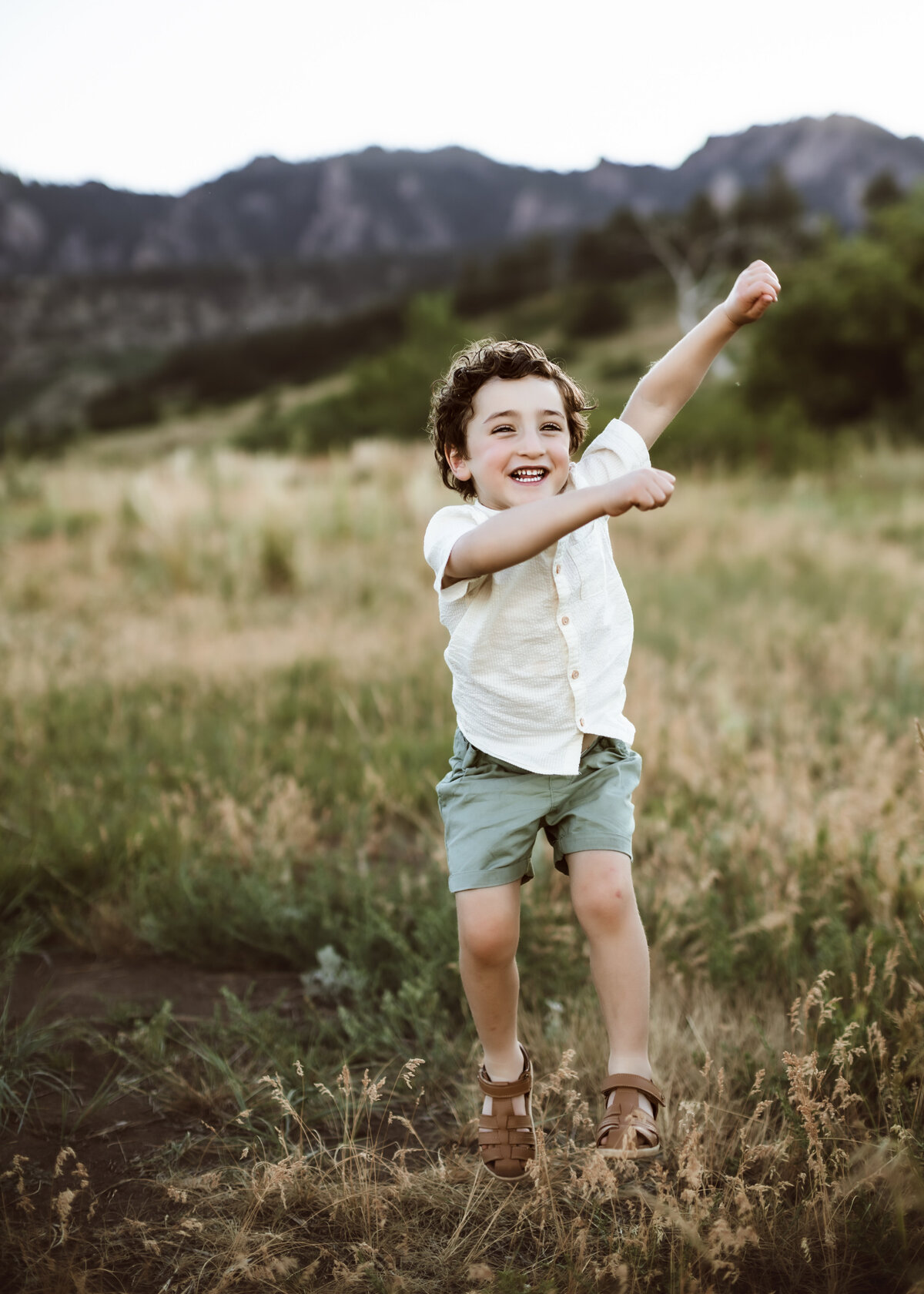 Young boy playing in a field during summertime photography session in Boulder colorado with Erin Jachimiak Photography