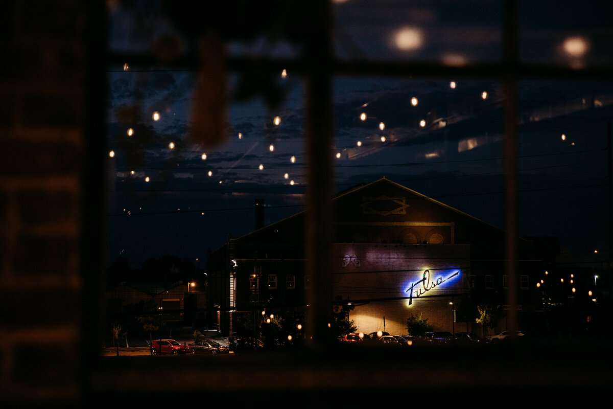 Nighttime view of a festive brewery venue seen through a window adorned with fairy lights