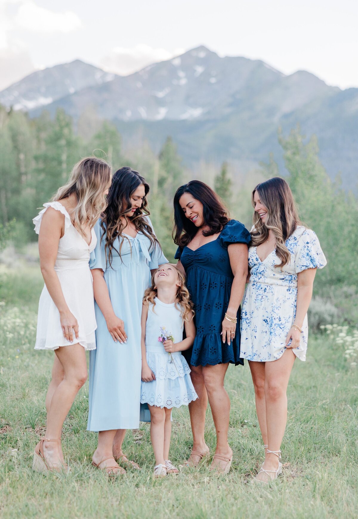 A young girl smiles while looking up to her mom, aunts and grandma in a field