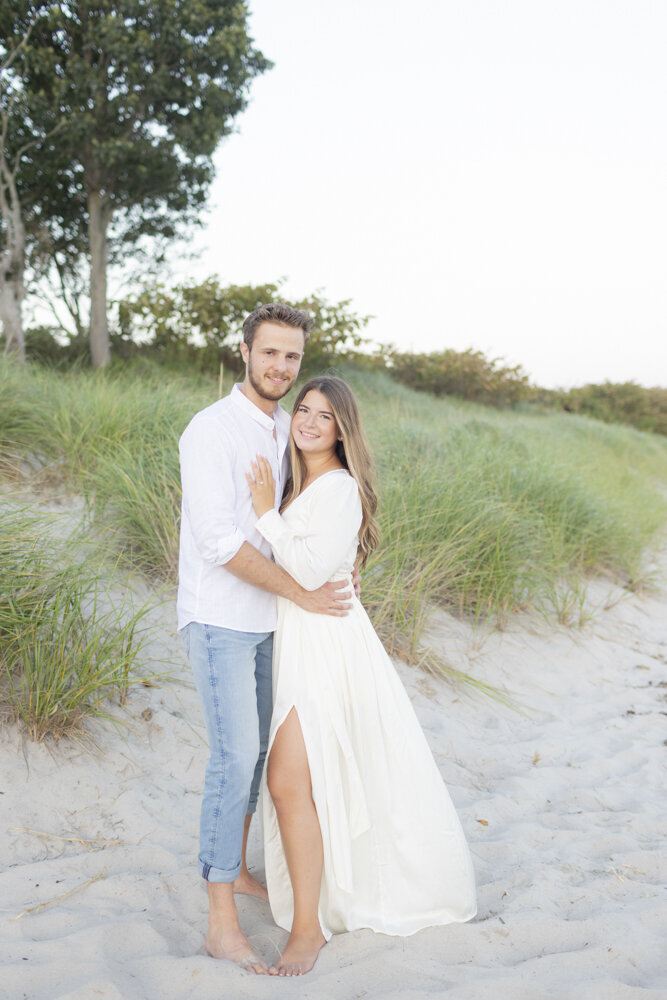 couple wearing white for engagement photos on the beach