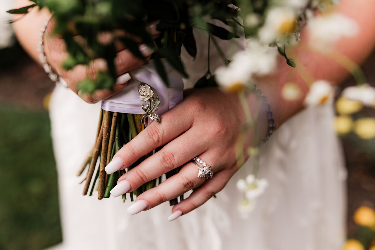 A close up shot of a brides wedding ring holding her bouquet.