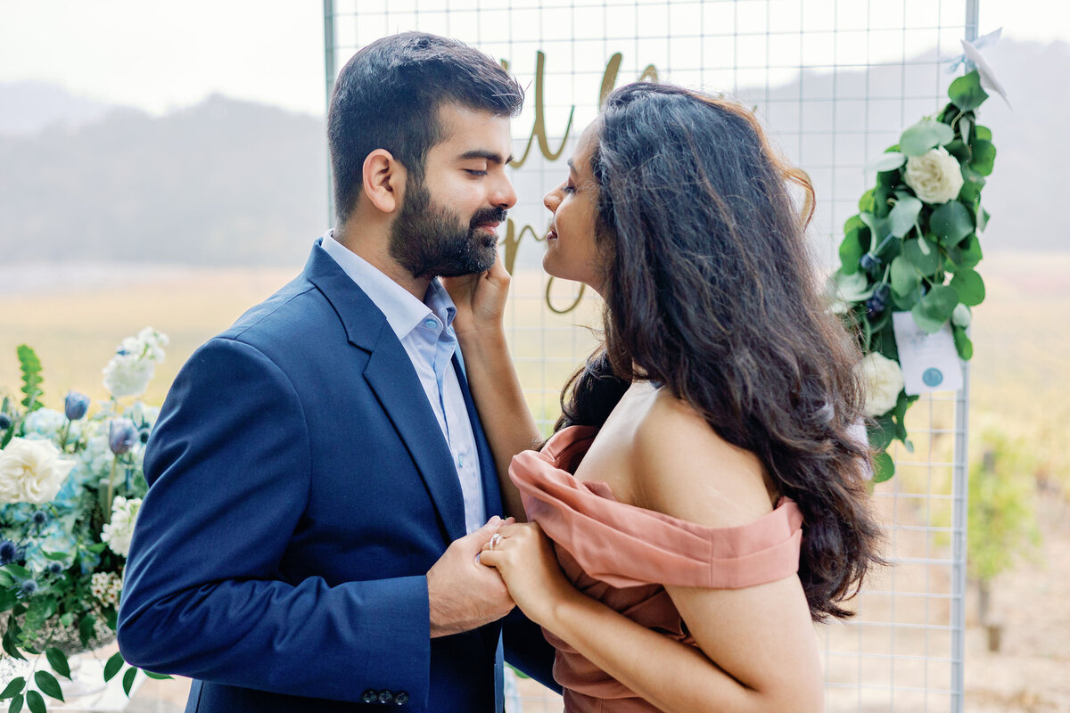 candid engagement pictures with man and woman holding one hand together as the woman holds the mans face and leaning in to kiss him photographed by bay area photographers