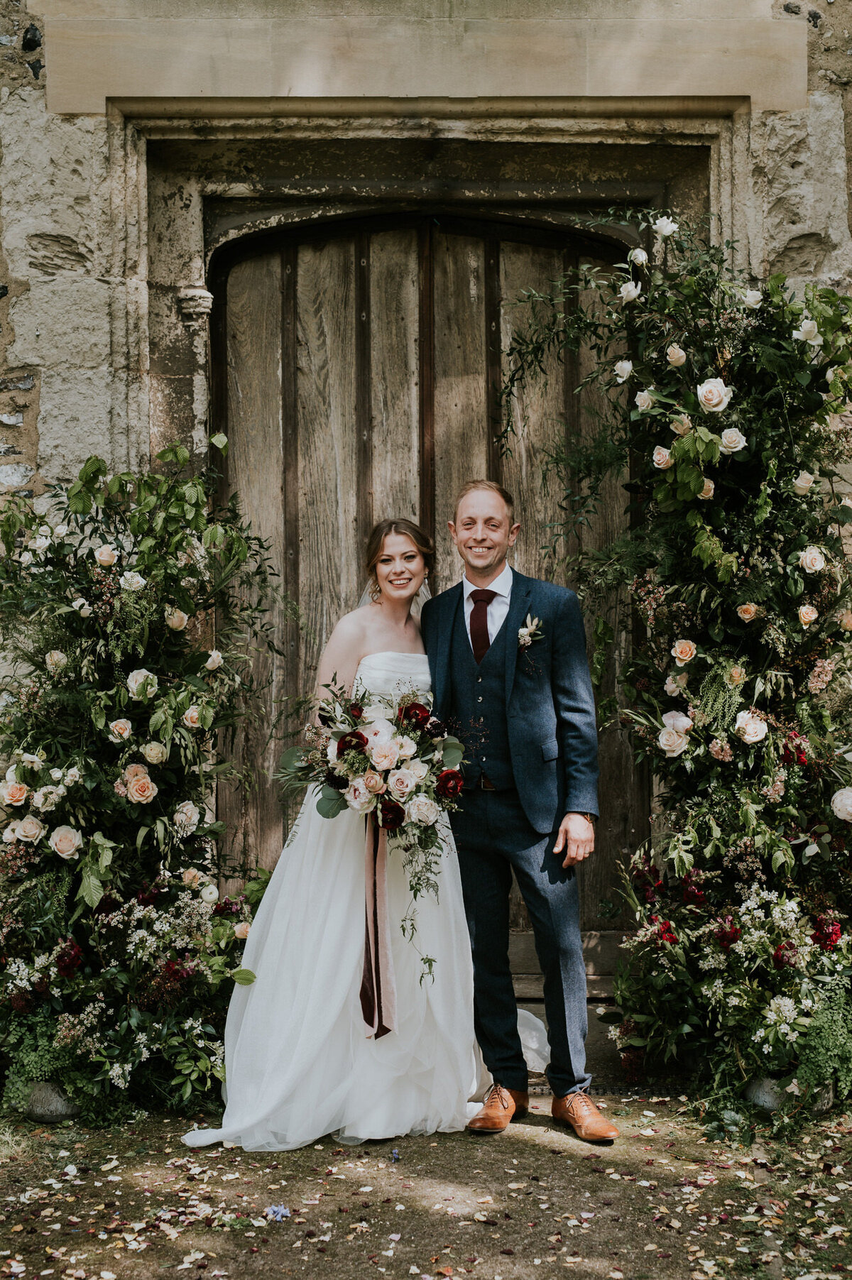 Bride and Groom posing in church doorway with flower arch