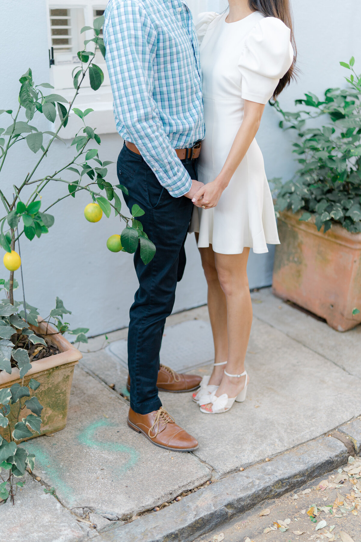 Lemon tree in downtown Charleston. Engaged couple holding hands on the sidewalk in front of historic Charleston home.