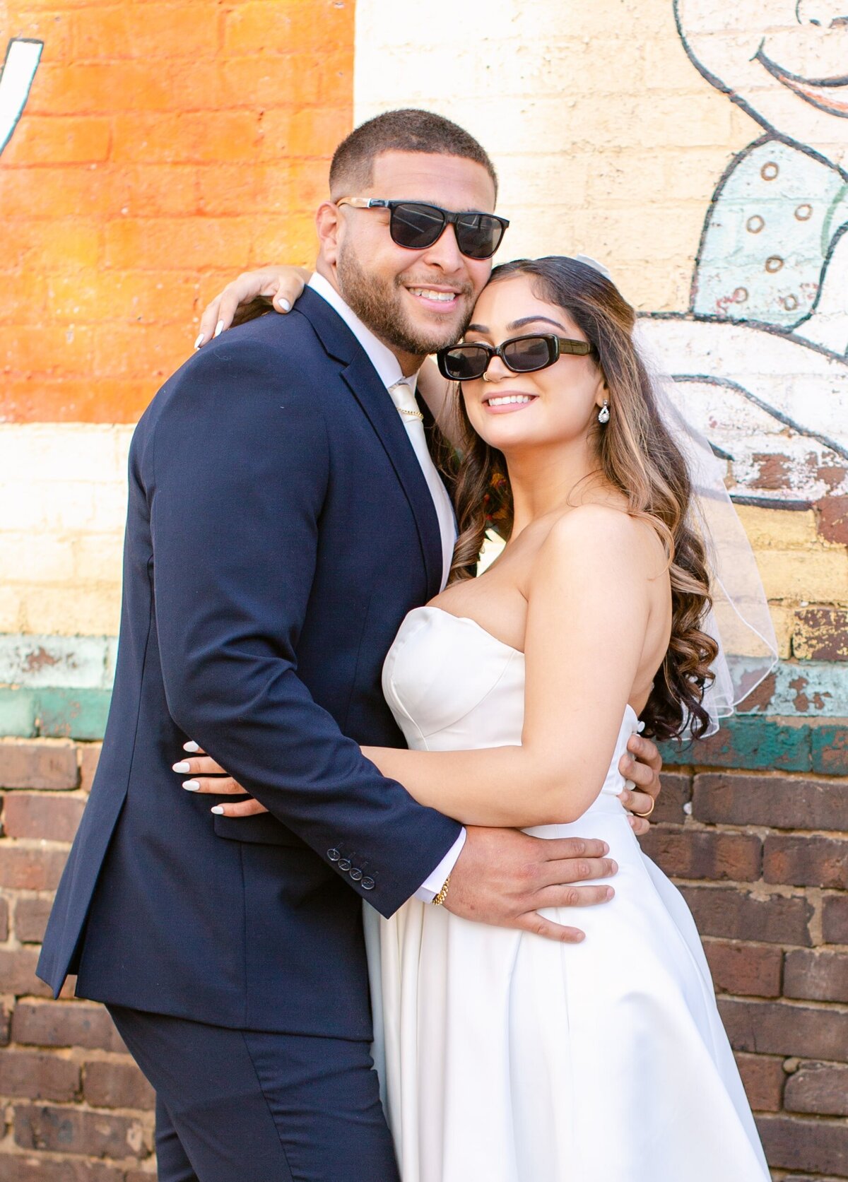 Bride and Groom with sunglasses on in front of brick wall in Culpeper, Virginia.