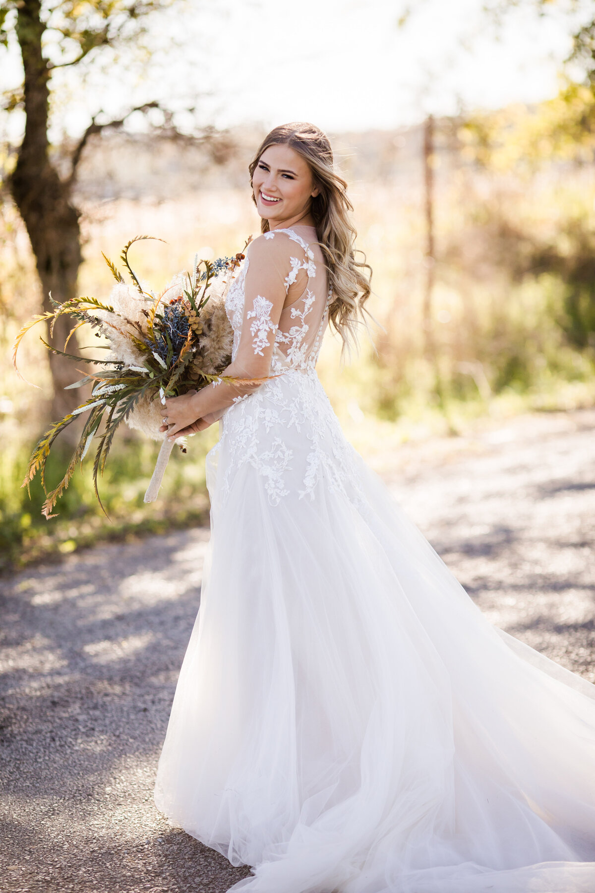 Bride looking over shoulder holding a large bouquet of pampas grass and dried flowers
