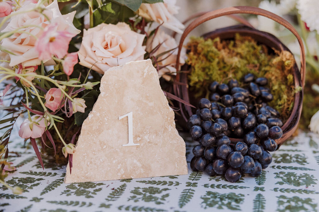 table number in stone surrounded by flowers and fruit bride and groom monserate winery wedding editorial, timeless, candid