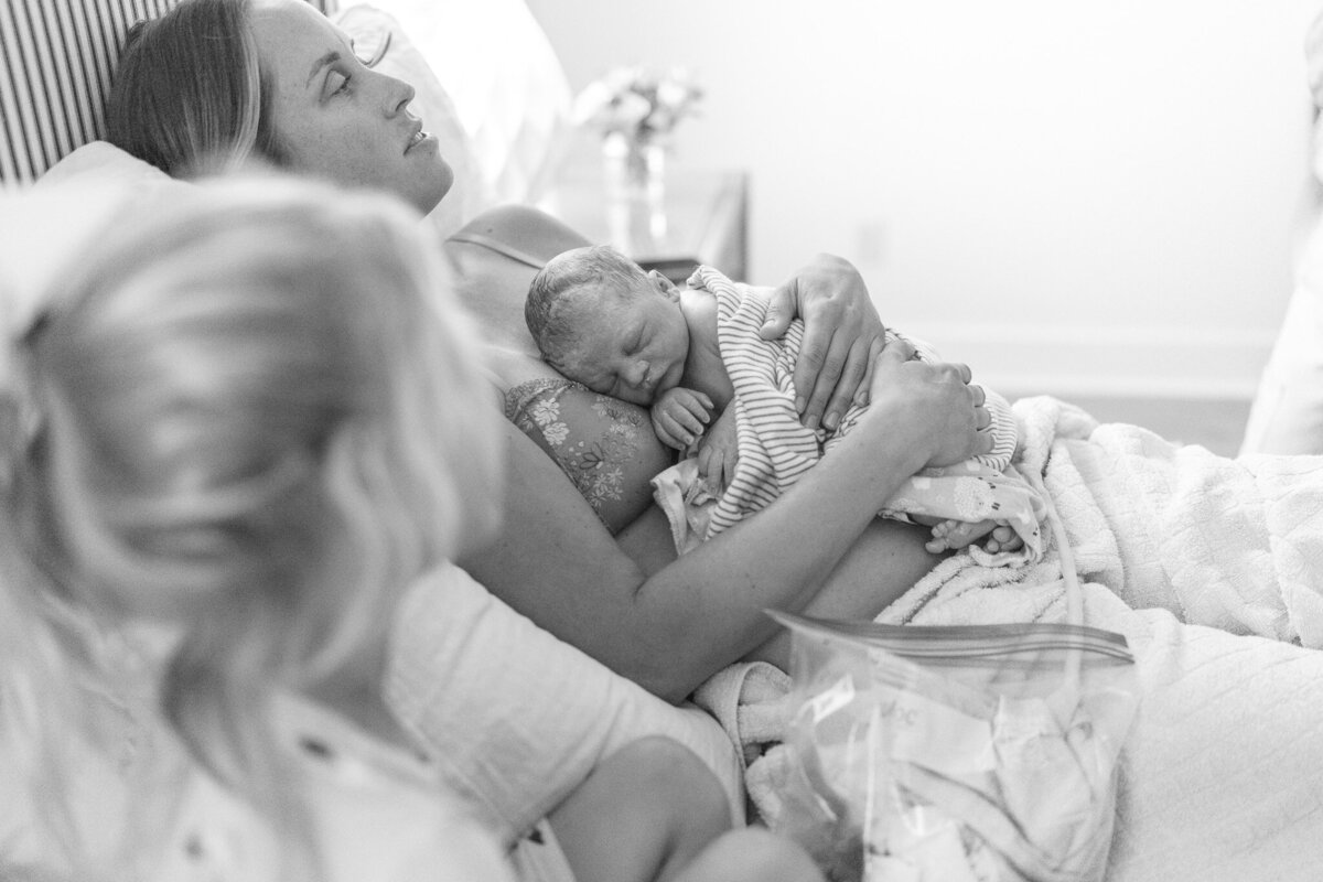 mom holding brand new baby after birthing baby at home