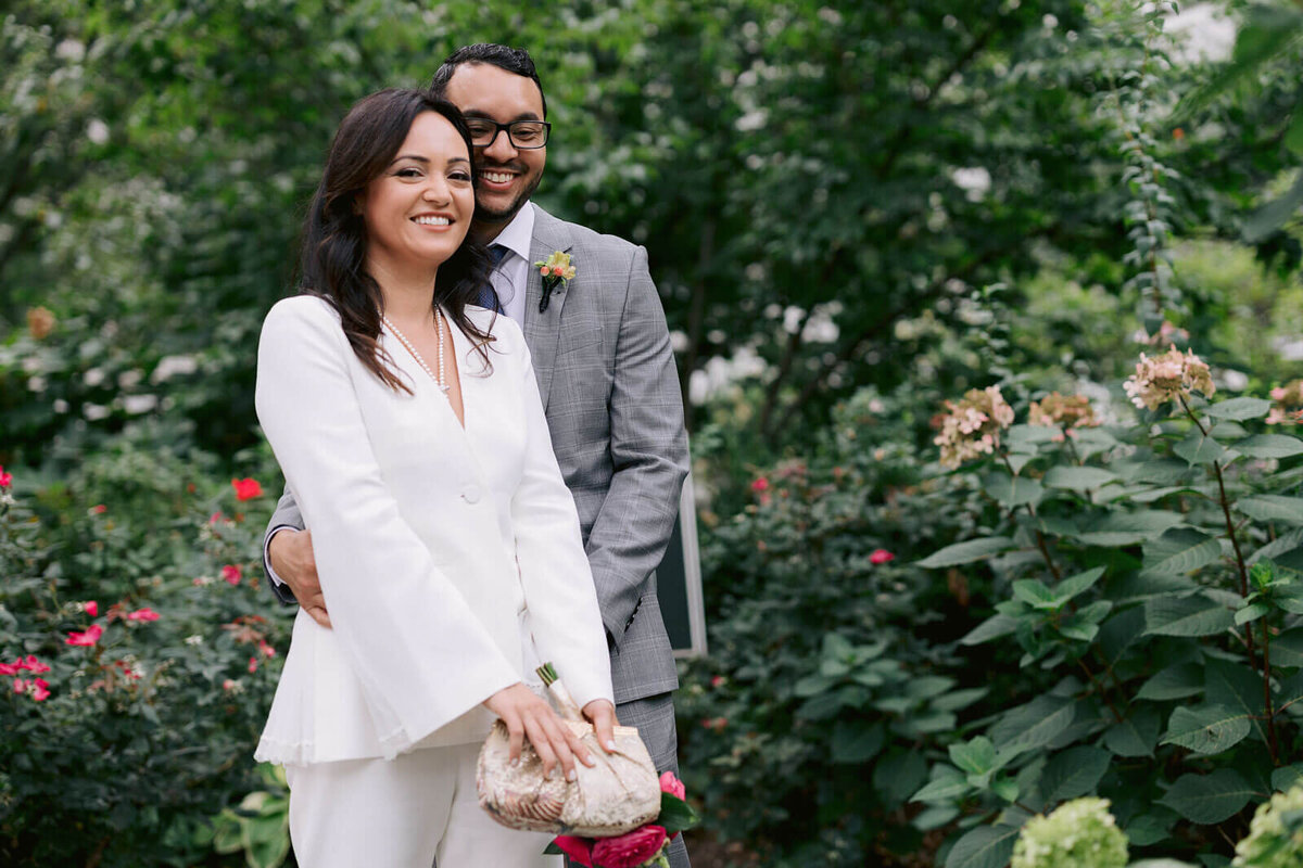 The bride and the groom are smiling in the NY City Hall Park. Image by Jenny Fu Studio