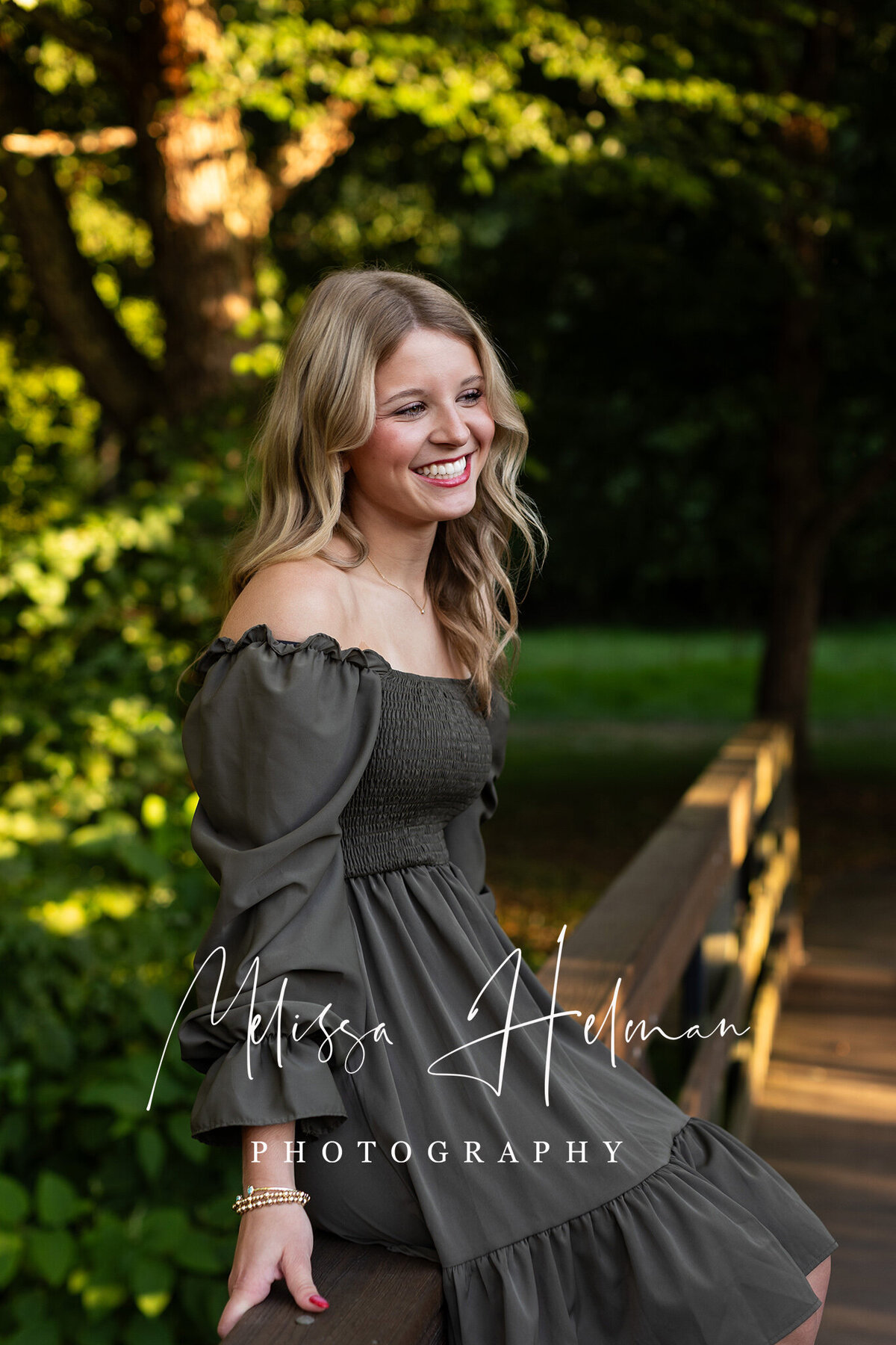 High school senior girl smiling in a grassy field at UPG campus in Greensburg during golden hour