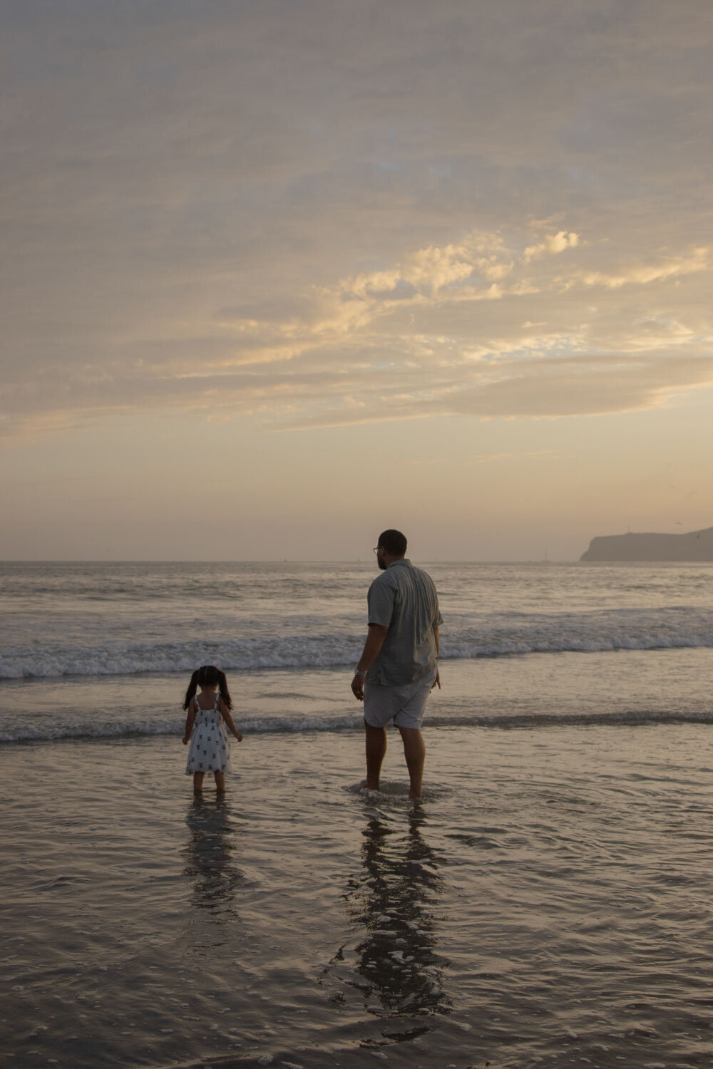 father and daughter walking up a sandy hill at sunset