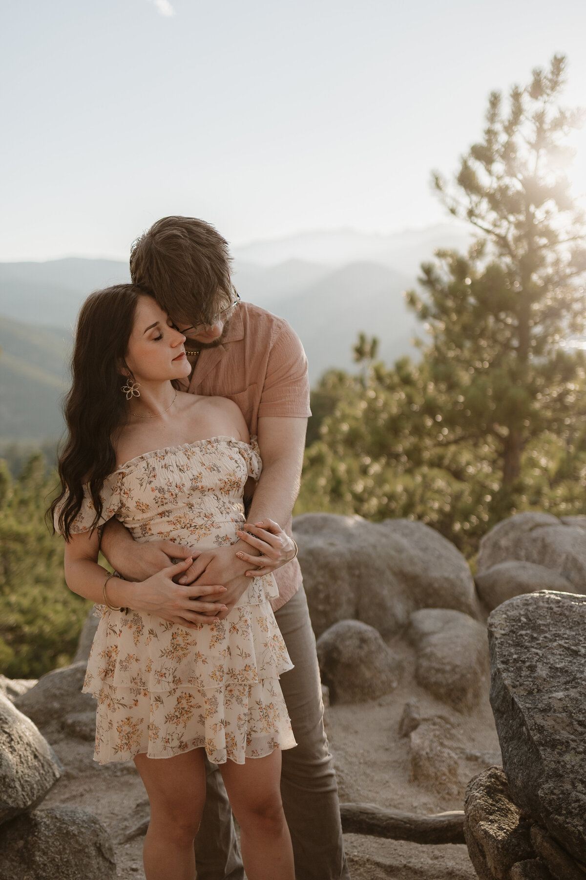 expectant parents arms wrapped around pregnant belly with temples together and softly smiling during lifestyle maternity session in boulder colorado
