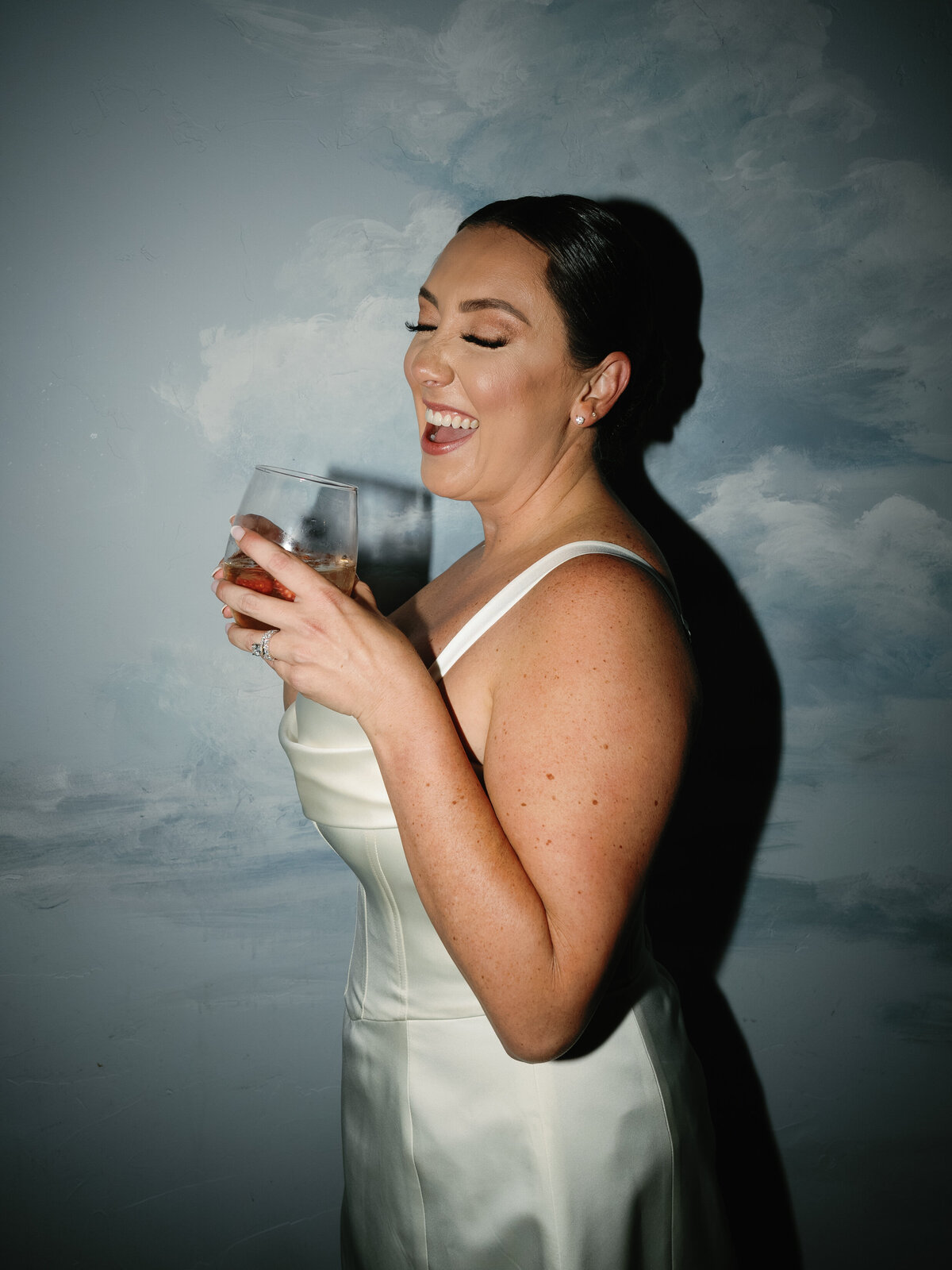 The bride laughs while holding a cocktail during her fall Castle Ladyhawke wedding celebration.