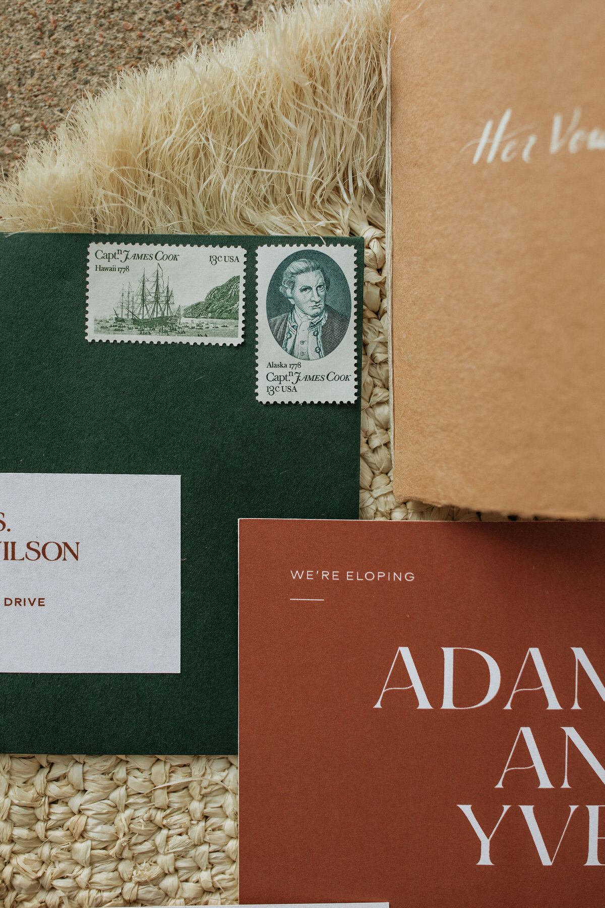 green envelope with burnt orange lettering and vintage stamps next to tan textured card stock with white lettering and burnt orange save the date card stock