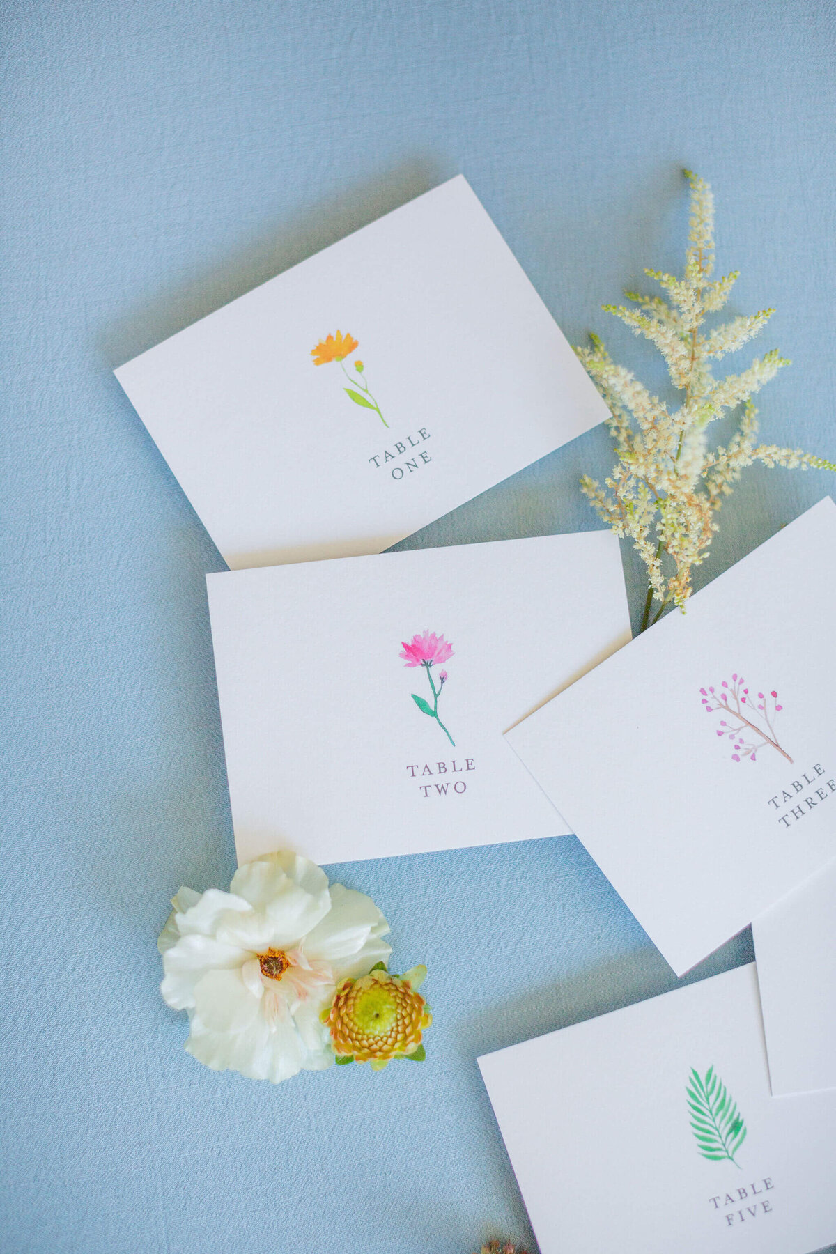 Escort card inserts painted with colorful flowers lie on a beautiful background